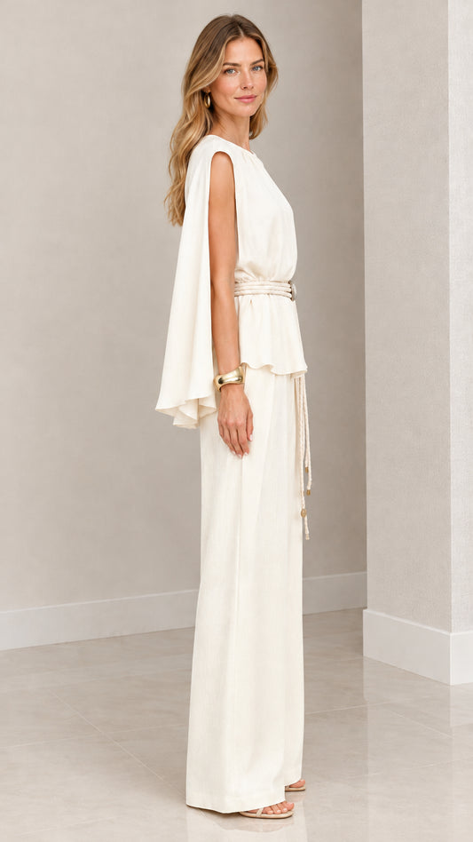 Side angle view of woman wearing cream cape sleeve top and wide leg trousers