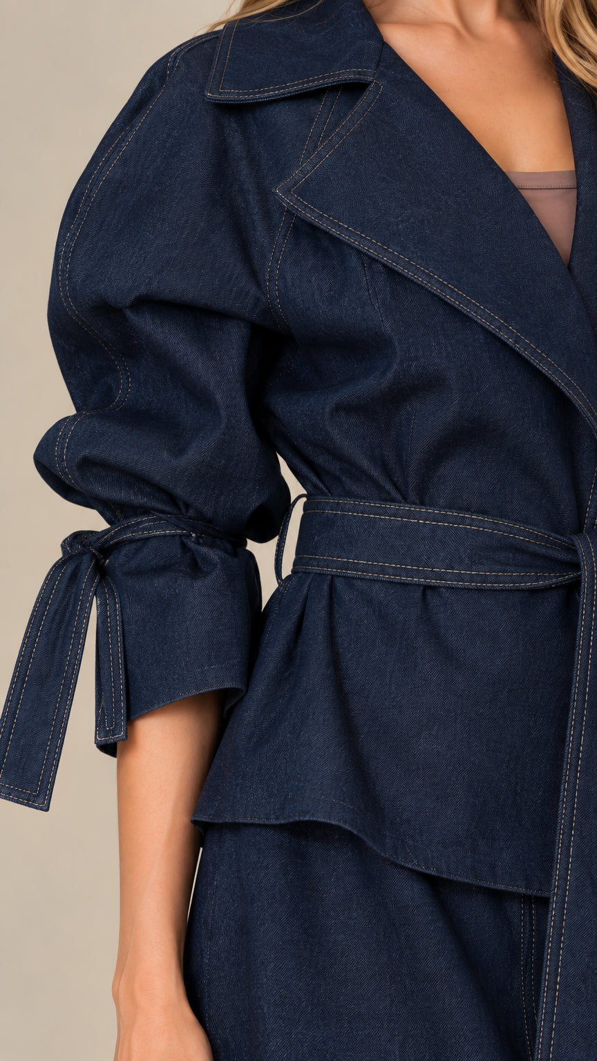 Close-up detail of navy blue jacket showing wide notch lapels, waist belt, and gathered tie sleeve cuff