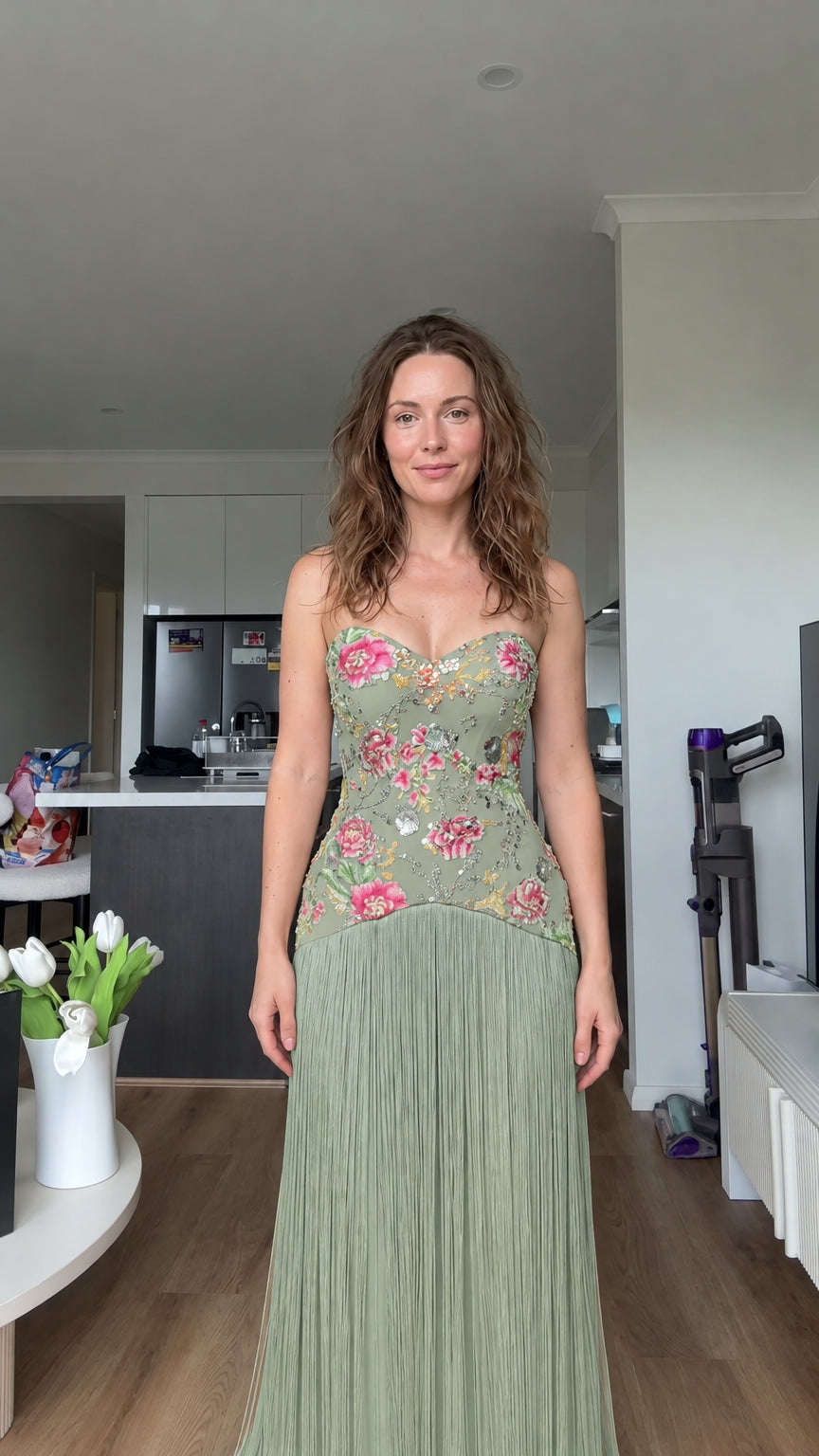 Woman wearing sage green floral embroidered strapless fringe gown