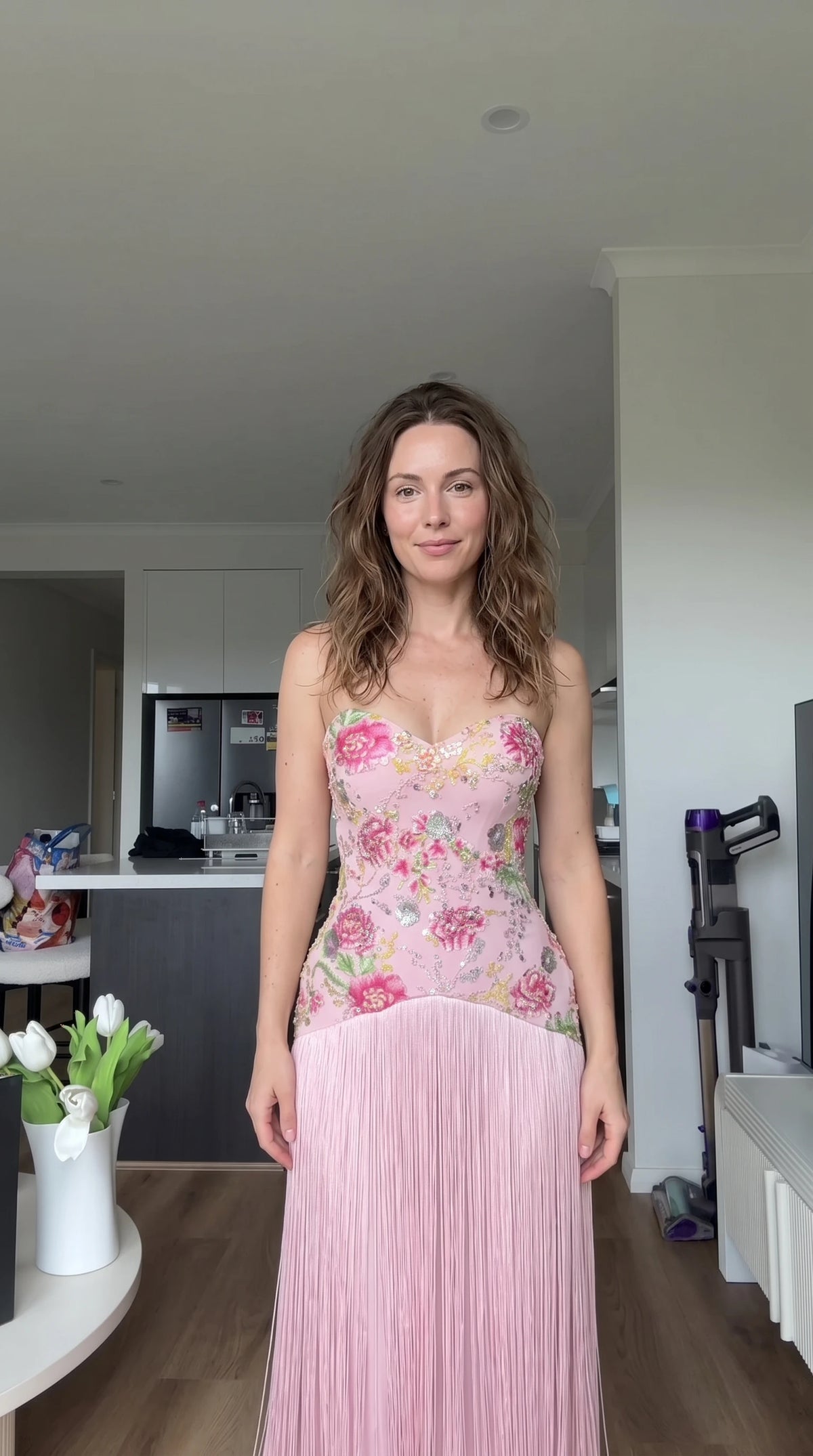 Front view of woman wearing strapless blush pink floral embroidered fringe maxi dress