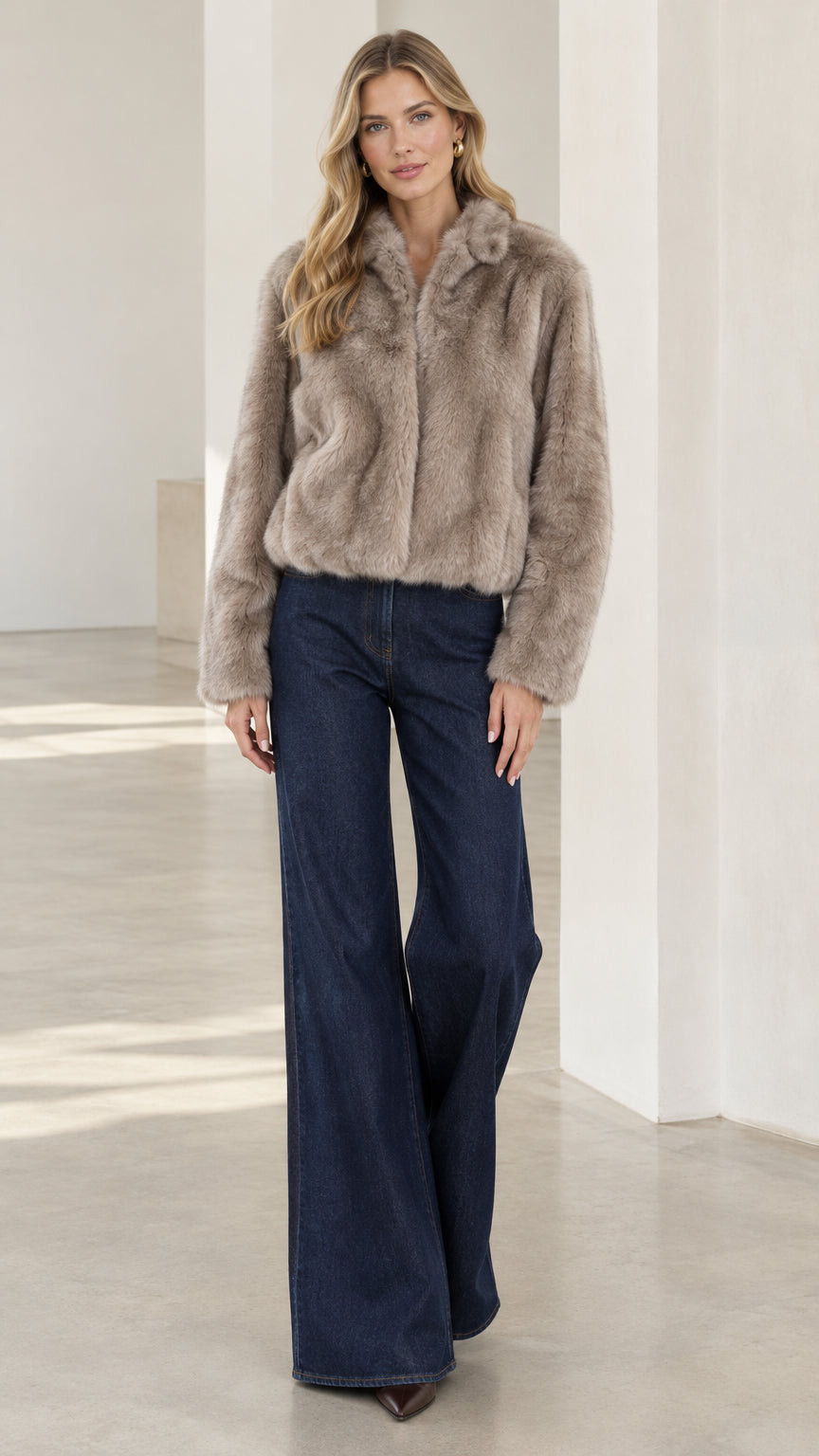 Front view of model wearing taupe cropped faux fur jacket with dark wide-leg jeans
