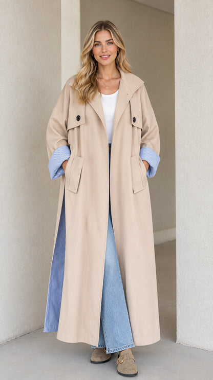 Front view of woman wearing beige maxi trench coat with striped cuff lining