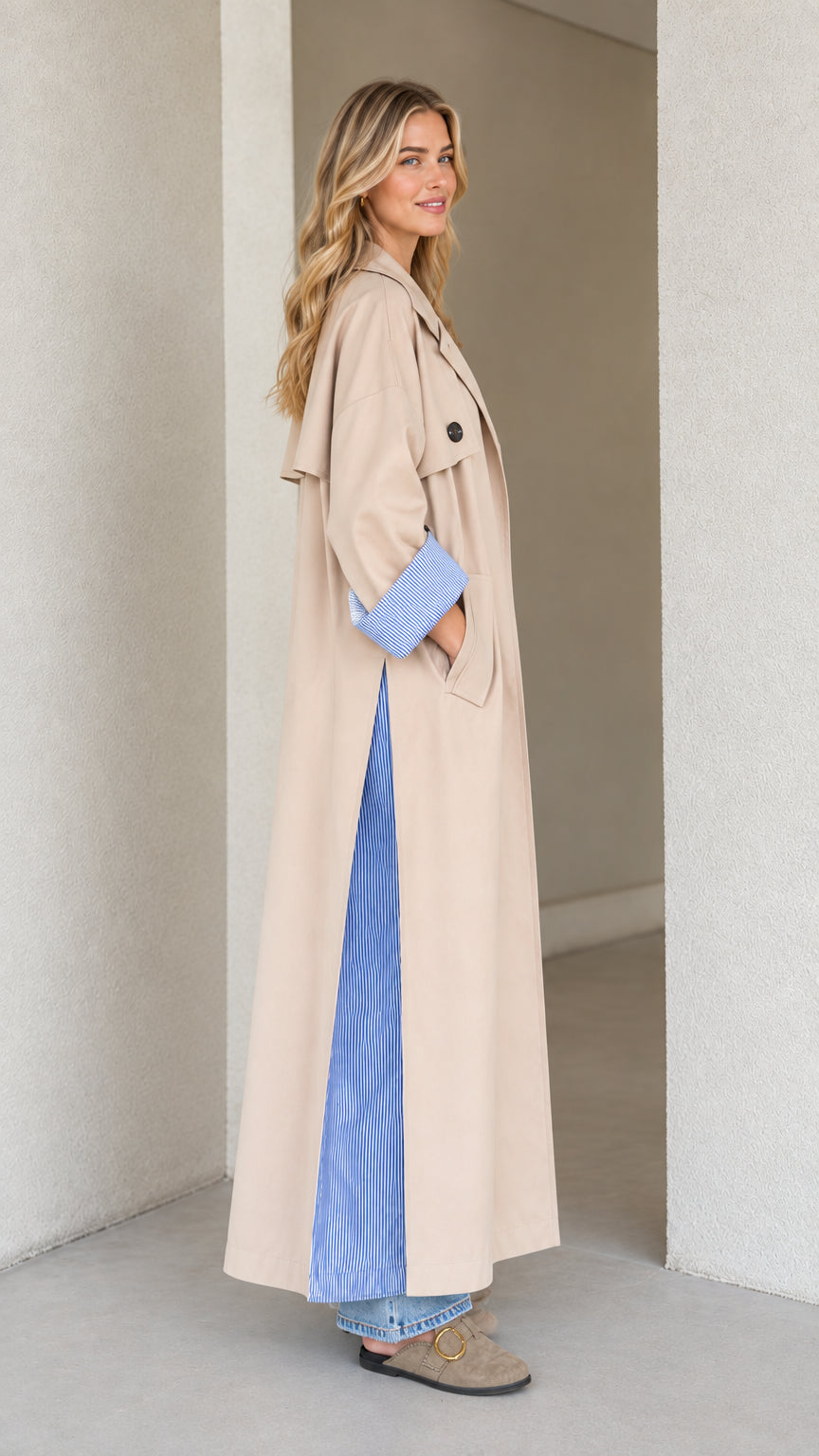 Side profile of woman in beige longline duster coat showing side slit detail
