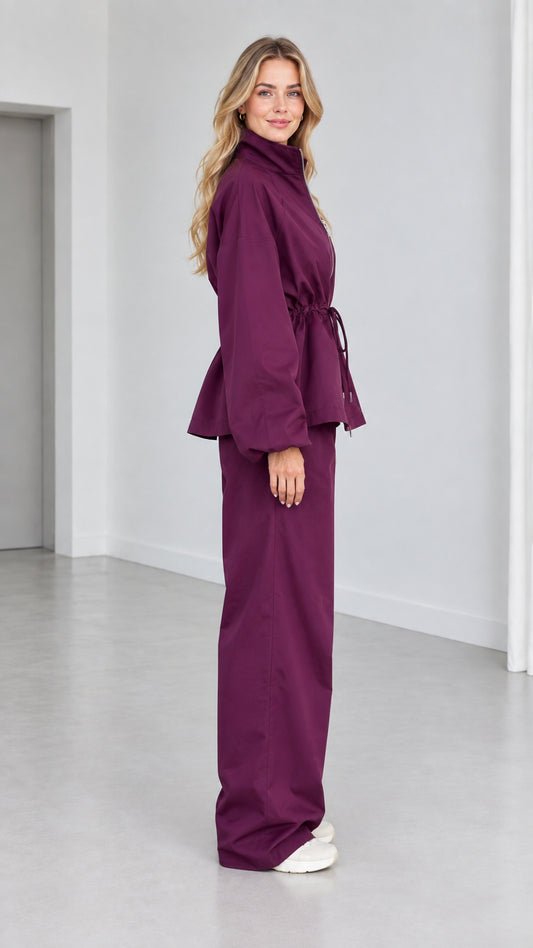 Side view of woman wearing plum matching zip jacket and wide-leg pants set