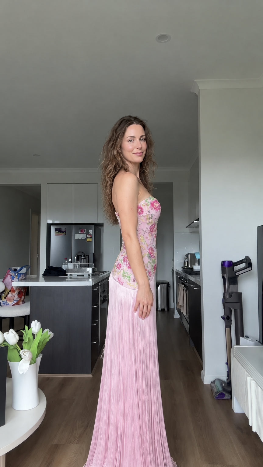 Side profile view of woman modeling blush pink embroidered fringe evening gown