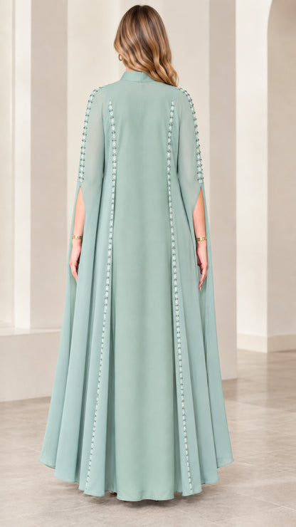 Back view of sage green maxi dress highlighting sweeping cape overlay