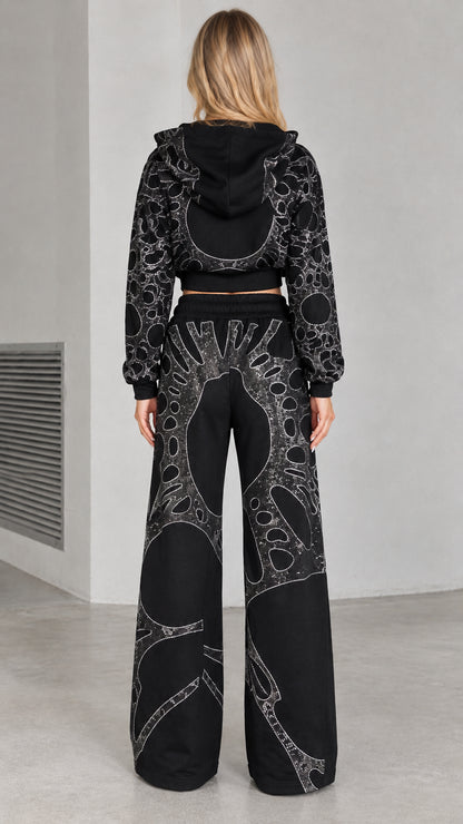 Back view of woman wearing black rhinestone zip hoodie and wide leg pants