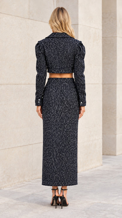 Back view of model wearing black tweed two-piece cropped blazer and skirt set