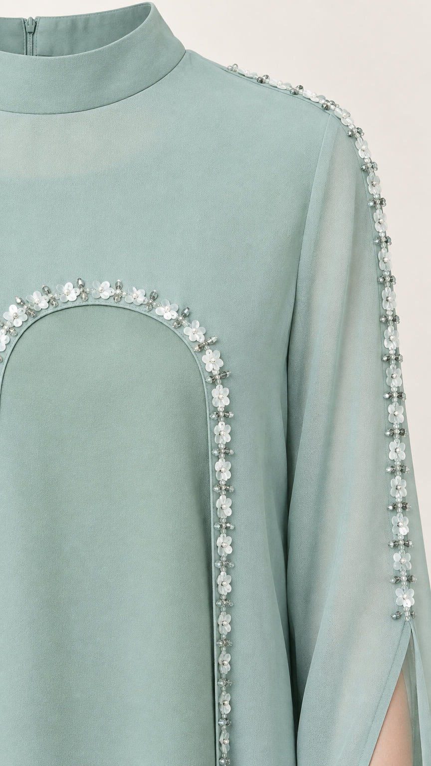 Close-up of mock neckline and floral beaded trim on sage green cape gown