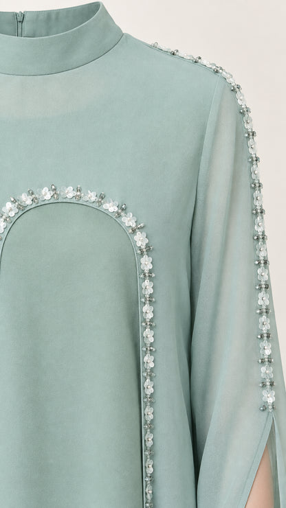 Close-up of mock neckline and floral beaded trim on sage green cape gown