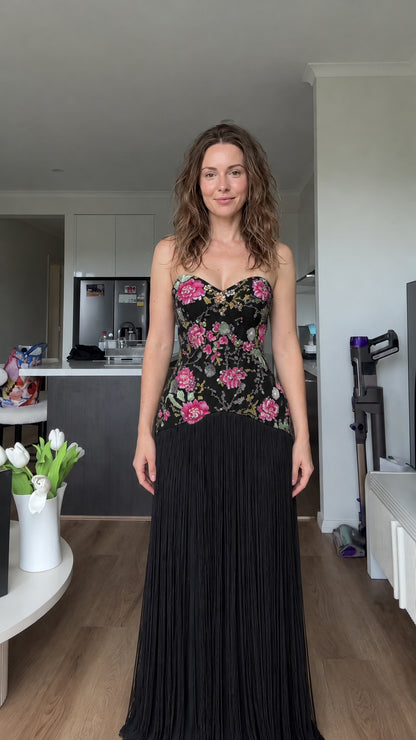 Woman wearing black floral embroidered strapless fringe maxi dress