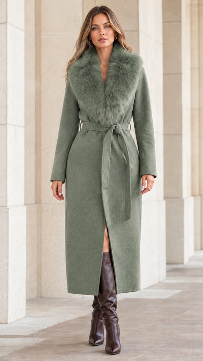 Front view of woman wearing sage green longline belted coat with matching faux fur collar